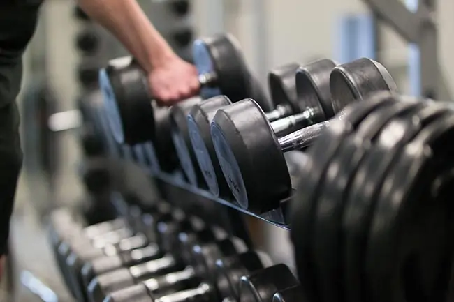man using dumbbells at fitness club